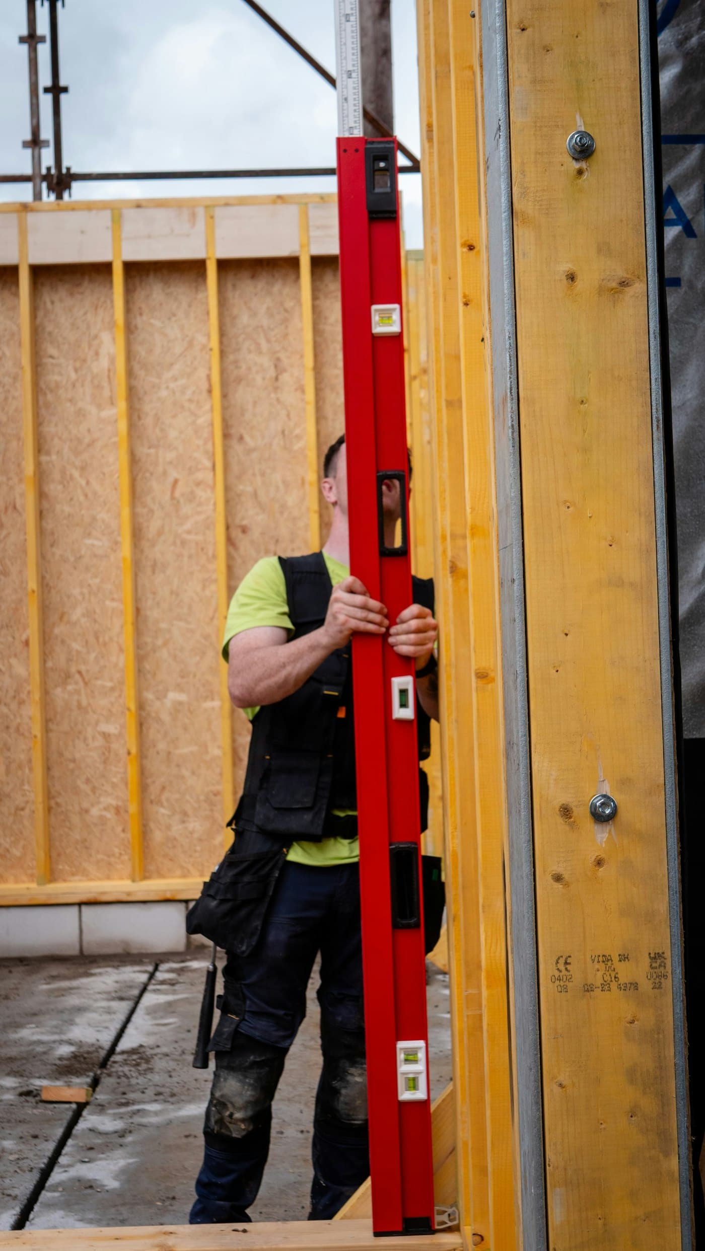 A builder checking a timber frame with a long spirit level
