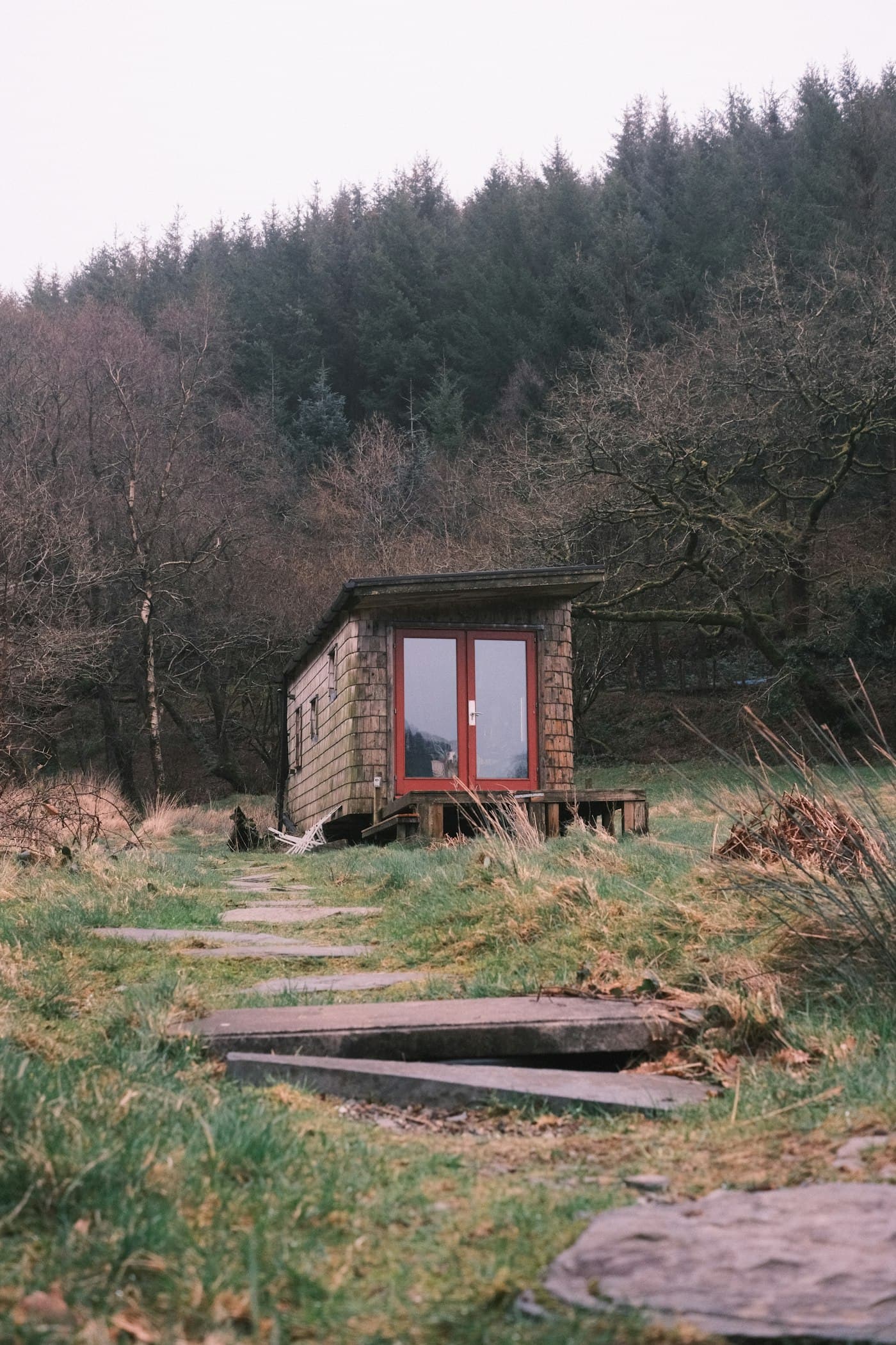 A small timber garden building with glazed doors at the end of a stepping-stone path