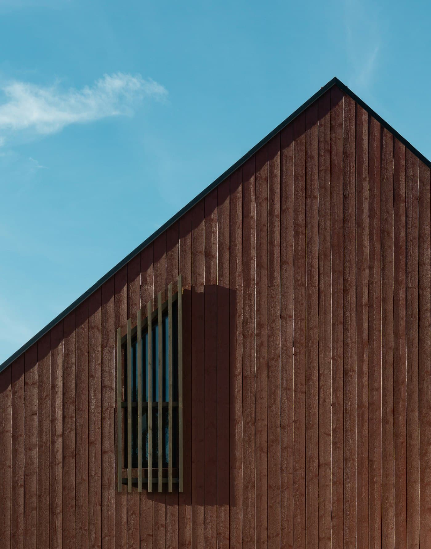 A dark-stained timber gable against a blue sky