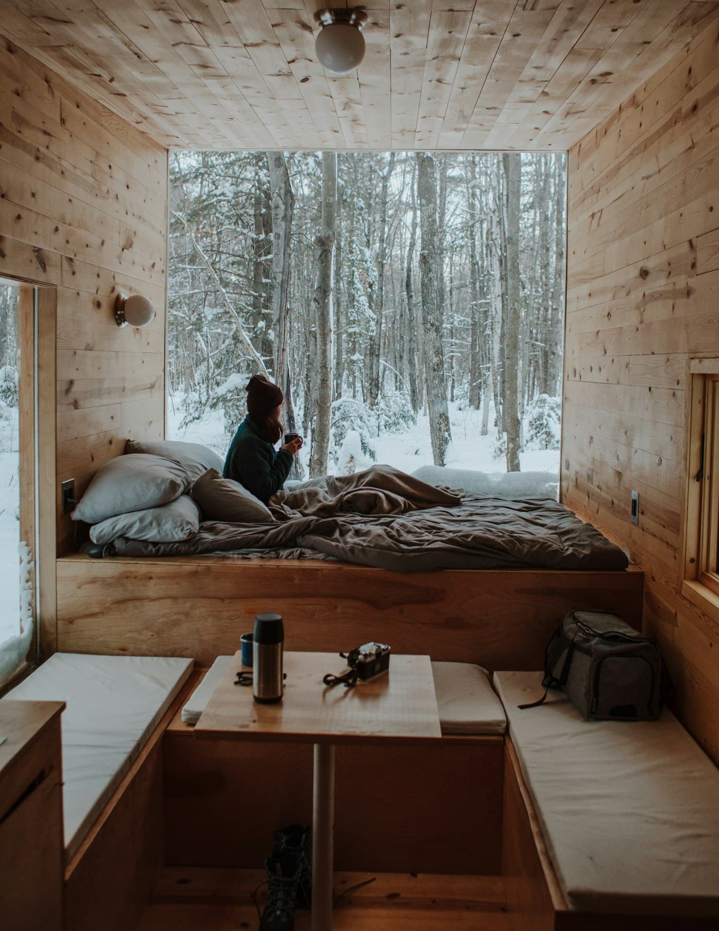 Someone sitting on a timber-lined window bed looking out at trees