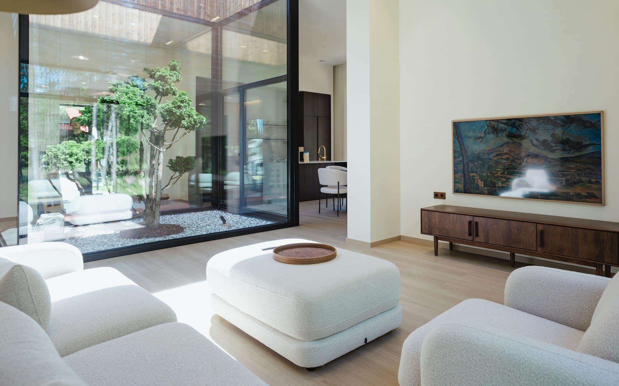 A living space with a pale ottoman and sliding glass doors onto a planted courtyard