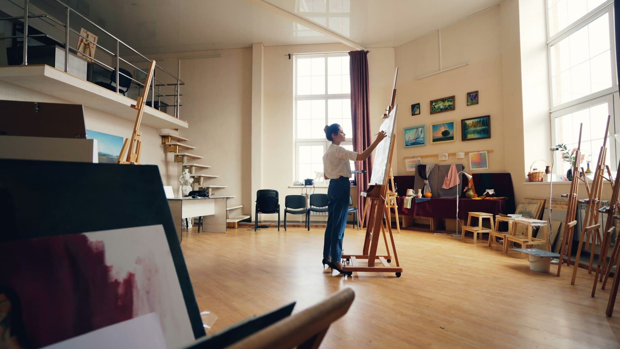 An artist working at an easel in a bright studio