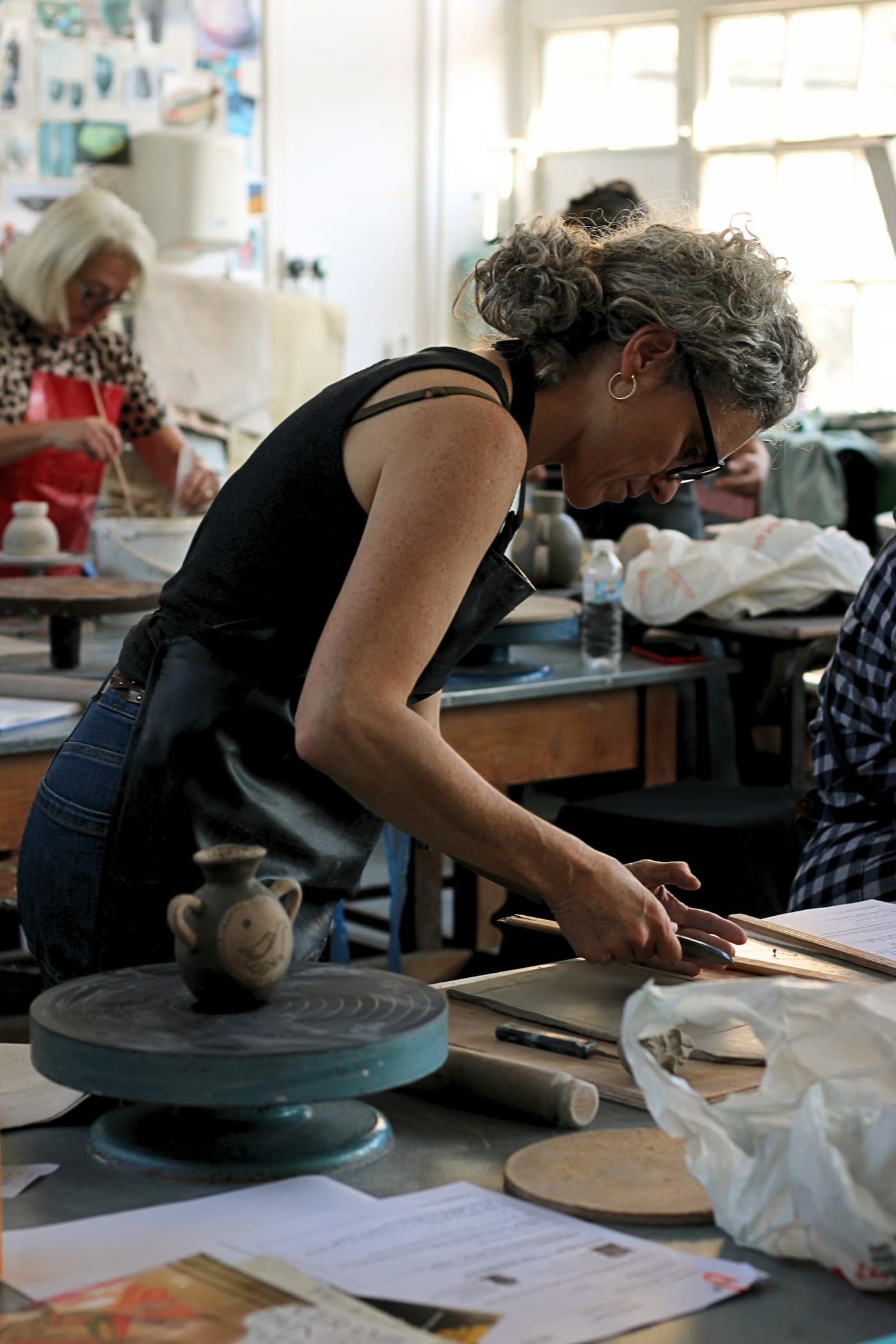 A potter shaping clay at a wheel in her studio