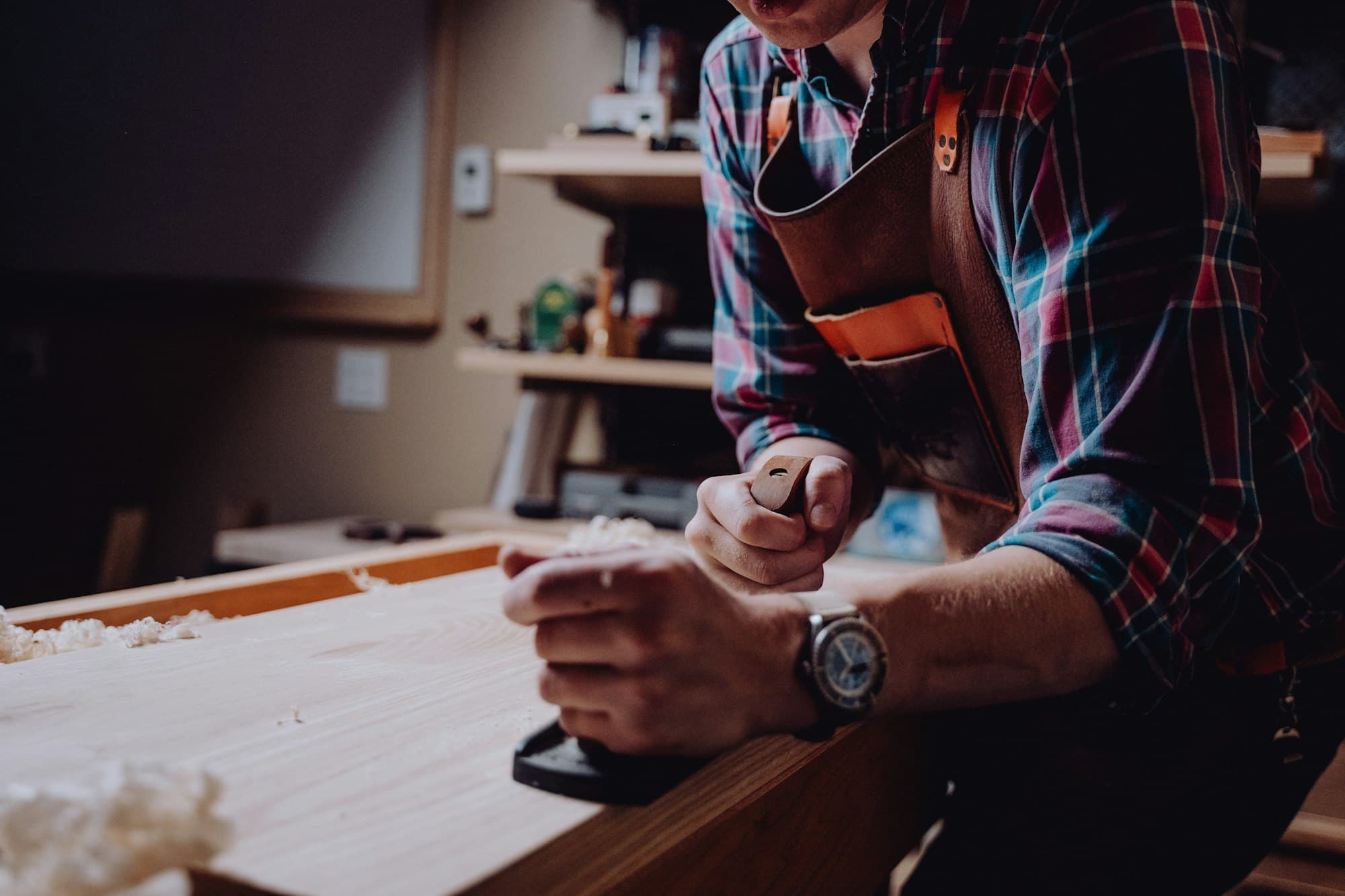 A joiner planing a length of timber in a workshop